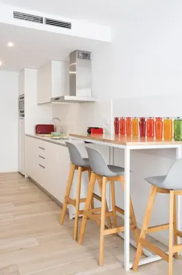 a kitchen with a table and stools in it at Urban Suites Sitges Apartments by PriorityVillas in Sitges