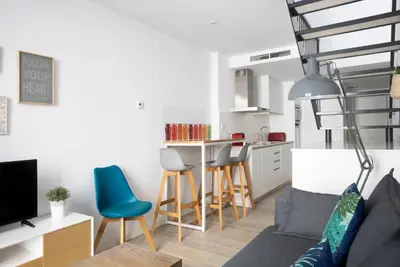 a living room with a couch and a kitchen at Urban Suites Sitges Apartments by PriorityVillas in Sitges