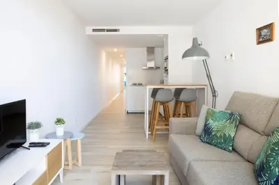 a living room with a couch and a kitchen at Urban Suites Sitges Apartments by PriorityVillas in Sitges