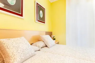 a bedroom with a white bed with yellow walls at Click&Flat Fira Gran Via in Hospitalet de Llobregat