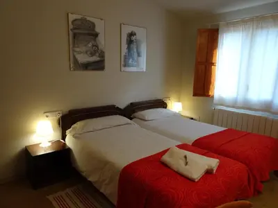 a bedroom with two beds with red sheets and two lamps at Can Seuba in Rellinars