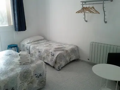 a small room with two beds and a table at Hostal River in Barcelona