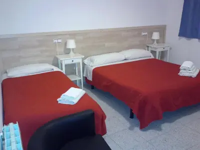 a hotel room with two beds and a chair at Hostal River in Barcelona