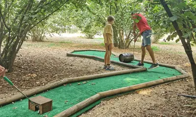 two men playing a game of golf on a putting green at Agroturisme Can Burguès in Santa Eulalia de Ronsaná