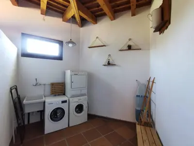 a laundry room with a washing machine and a sink at Agroturisme Can Burguès in Santa Eulalia de Ronsaná