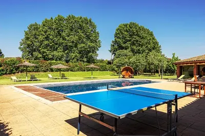 a ping pong table on a patio next to a pool at Agroturisme Can Burguès in Santa Eulalia de Ronsaná