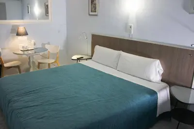 a hotel room with a large bed and a table at Hotel Alexandra Sitges in Sitges
