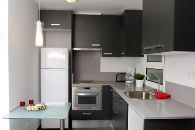 a kitchen with black cabinets and a plate of food on a table at Sant Pau Terraces Apartments in Barcelona