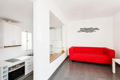 a red couch in a kitchen with white cabinets at Sant Pau Terraces Apartments in Barcelona