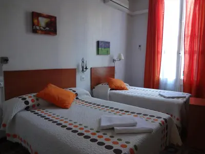 two beds in a hotel room with orange pillows at Hostal Lima in Barcelona