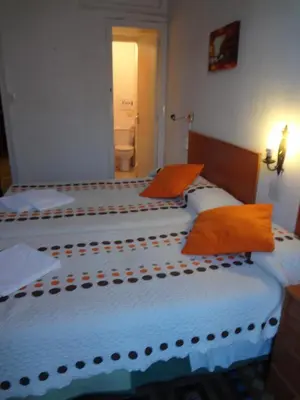 two beds in a hotel room with orange pillows at Hostal Lima in Barcelona