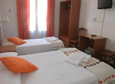 a hotel room with three beds and a television at Hostal Lima in Barcelona