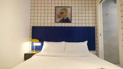 a bed with a blue headboard in a room at Arte Suites by Olala! - Smart Stay in Hospitalet de Llobregat