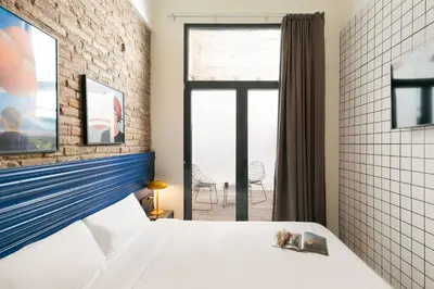 a bedroom with a white bed and a brick wall at Arte Suites by Olala! - Smart Stay in Hospitalet de Llobregat