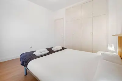 a white bedroom with a white bed and a couch at Quiet, Ultra-Central Stay KM0 for 3 in Barcelona