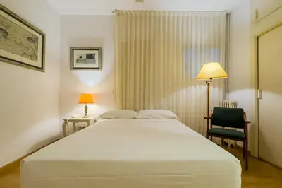 a bedroom with a large white bed and a chair at ENRIQUE GRANADOS in Barcelona