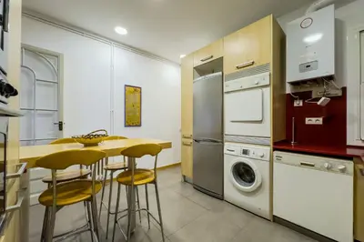 a kitchen with a table and chairs and a washer and dryer at ENRIQUE GRANADOS in Barcelona