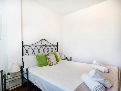 a bedroom with a bed with white sheets and green pillows at Amazing Seaview Apartment by Hello Homes Sitges in Sitges
