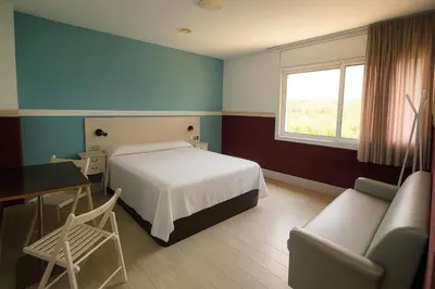 a bedroom with a bed and a desk and a window at Hotel Consentido in Granollers