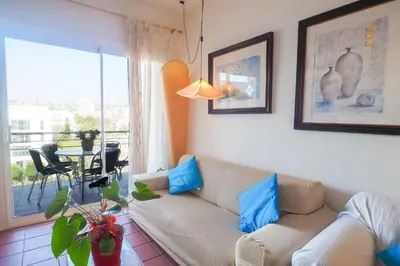 a living room with a couch with blue pillows at Aquamarine Terrace Apartment by Hello Homes Sitges in Sitges