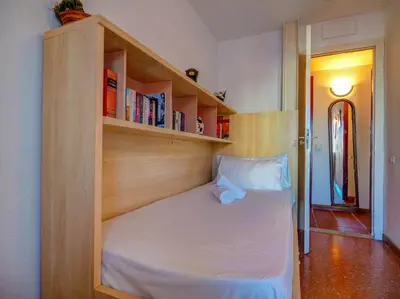 a bed in a room with a book shelf at Aquamarine Terrace Apartment by Hello Homes Sitges in Sitges