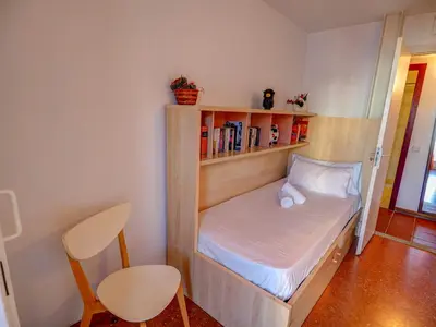 a small room with a bed and a book shelf at Aquamarine Terrace Apartment by Hello Homes Sitges in Sitges