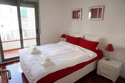 a bedroom with a large white bed with red pillows at Happy Holiday Beach Home in Sitges