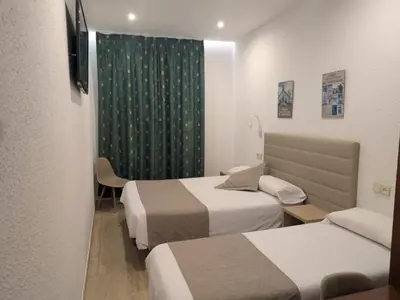 a hotel room with two beds and a green curtain at Hotel Mitus in Canet de Mar