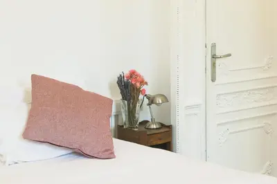a vase of flowers on a table next to a bed at La Casa Gran B&B in Barcelona