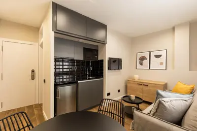 a kitchen and living room with a couch and a table at Apartamentos Laforja in Barcelona