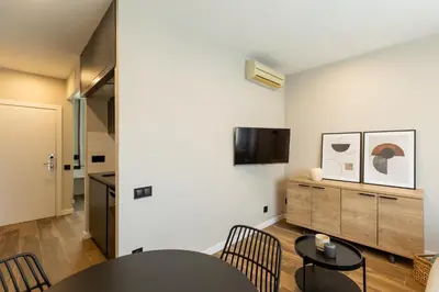 a living room with a table and chairs and a tv at Apartamentos Laforja in Barcelona