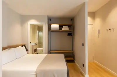 a bedroom with a white bed and a bathroom at Apartamentos Laforja in Barcelona