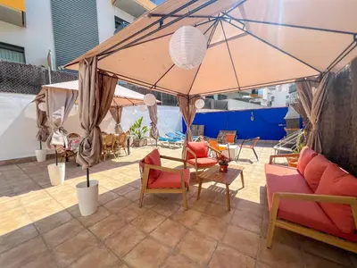 a large umbrella on a patio with chairs and tables at The Beach House Paradise by Hello Homes Sitges in Sitges