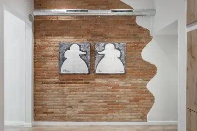 two pieces of art on a brick wall at Art House Fira Apartments in Barcelona