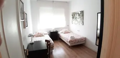 a bedroom with two beds and a table and a window at Piso Zona Plaza España, junto a Montjuic, in Barcelona
