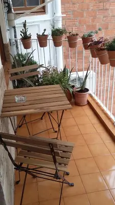 a table and bench on a balcony with potted plants at Piso Zona Plaza España, junto a Montjuic, in Barcelona