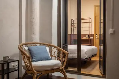 a wicker chair with a blue pillow in a bedroom at BYPILLOW Ramblas in Barcelona