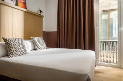a bed in a room with a large window at BYPILLOW Ramblas in Barcelona
