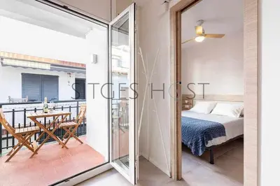 a bedroom with a bed and a balcony with a table at Sitges CENTRAL - En el corazón de Sitges in Sitges