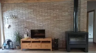 a living room with a tv and a brick wall at Cal Puó Turismo Rural in Collsuspina