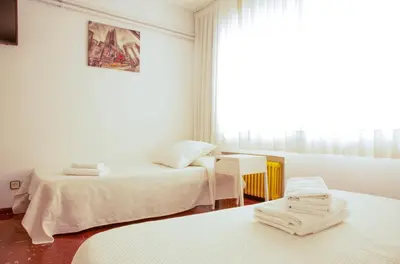 a white room with two beds and a window at Barcelona City Street Hostal in Barcelona