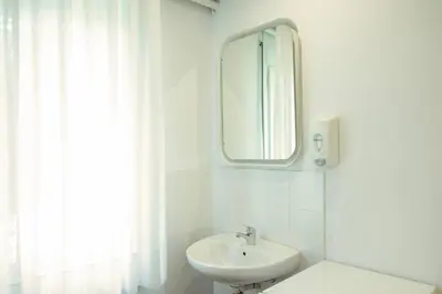 a white bathroom with a sink and a mirror at Barcelona City Street Hostal in Barcelona