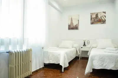 a white room with two beds and a radiator at Barcelona City Street Hostal in Barcelona