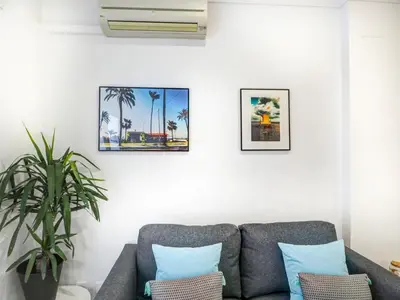 a living room with a couch and pictures on the wall at White Center Apartment by Hello Homes Sitges in Sitges