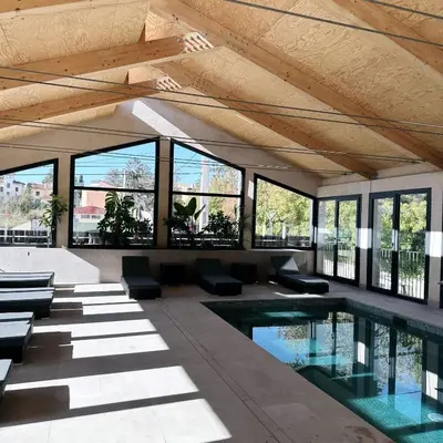 a swimming pool in a building with windows at La Violeta HOTEL SPA & CHILL OUT in Castelltersol