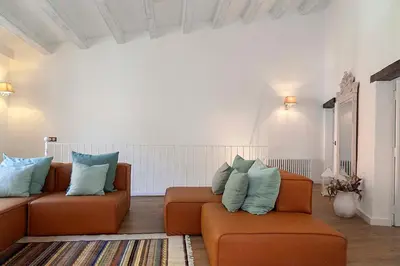a living room with an orange couch and blue pillows at A historic XVI century beach home near Barcelona in Caldes d'Estrac