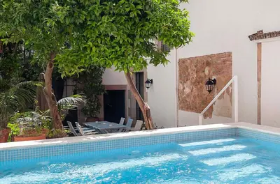 a swimming pool in front of a house with trees at A historic XVI century beach home near Barcelona in Caldes d'Estrac