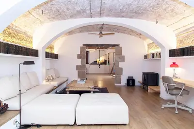 a living room with a white couch and a table at A historic XVI century beach home near Barcelona in Caldes d'Estrac