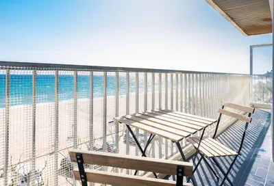a balcony with a table and bench on the beach at HomeHolidaysRentals Etoile in Calella