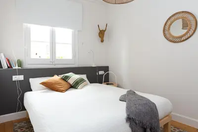 a bedroom with a bed with white sheets and a mirror at Casa Cosi - Francoli 1 in Barcelona